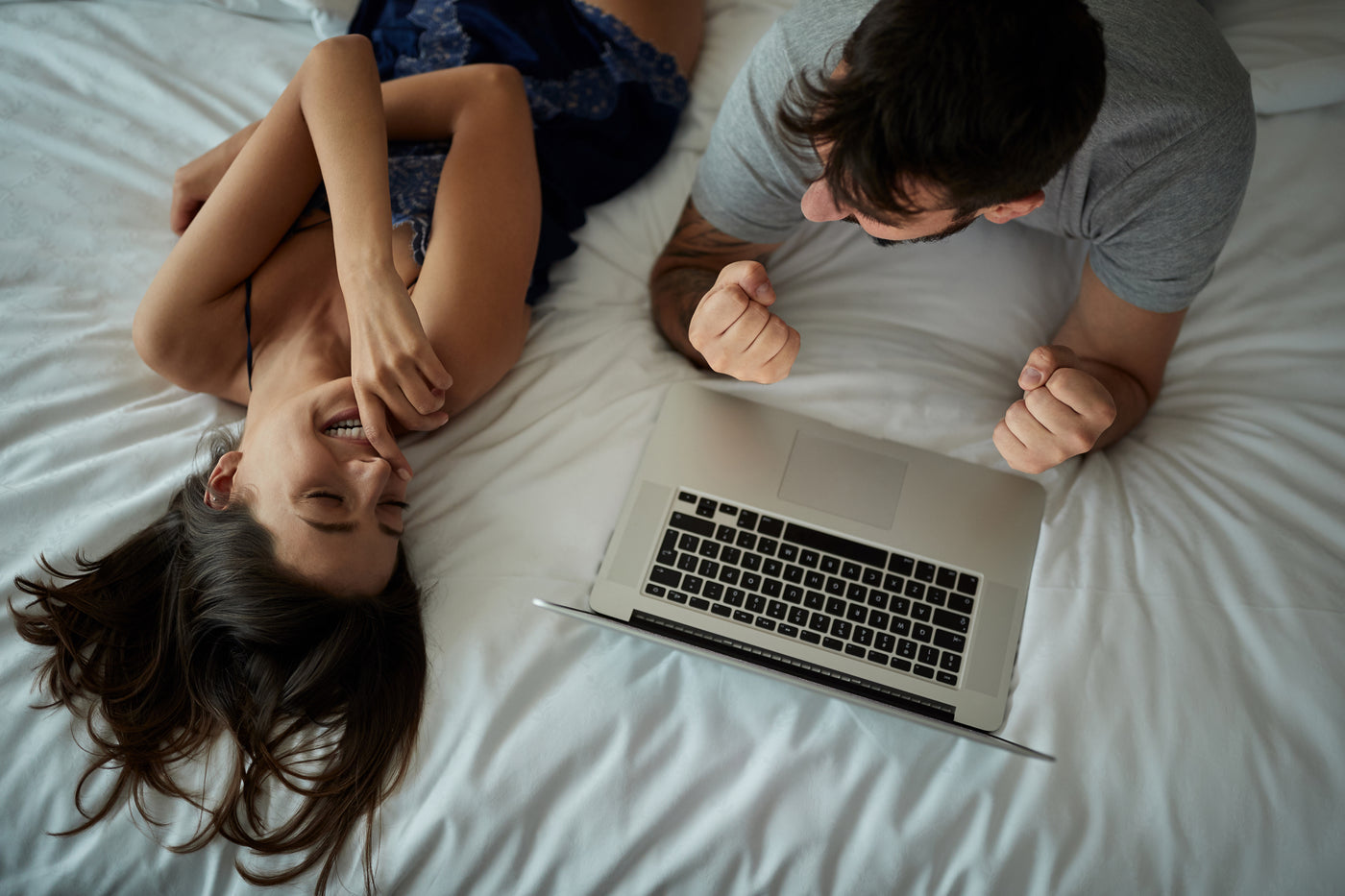 Couple laying on bed with mac