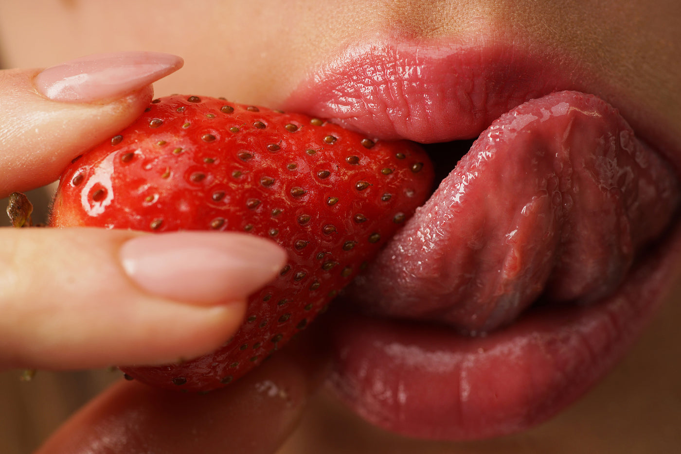 Woman holding strawberry on tongue 