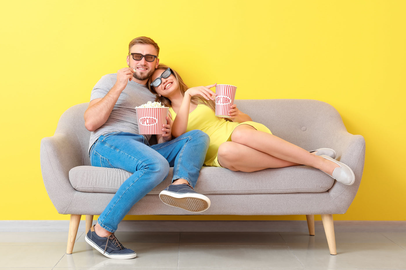 Couple eating popcorn, watching tv while sitting on couch