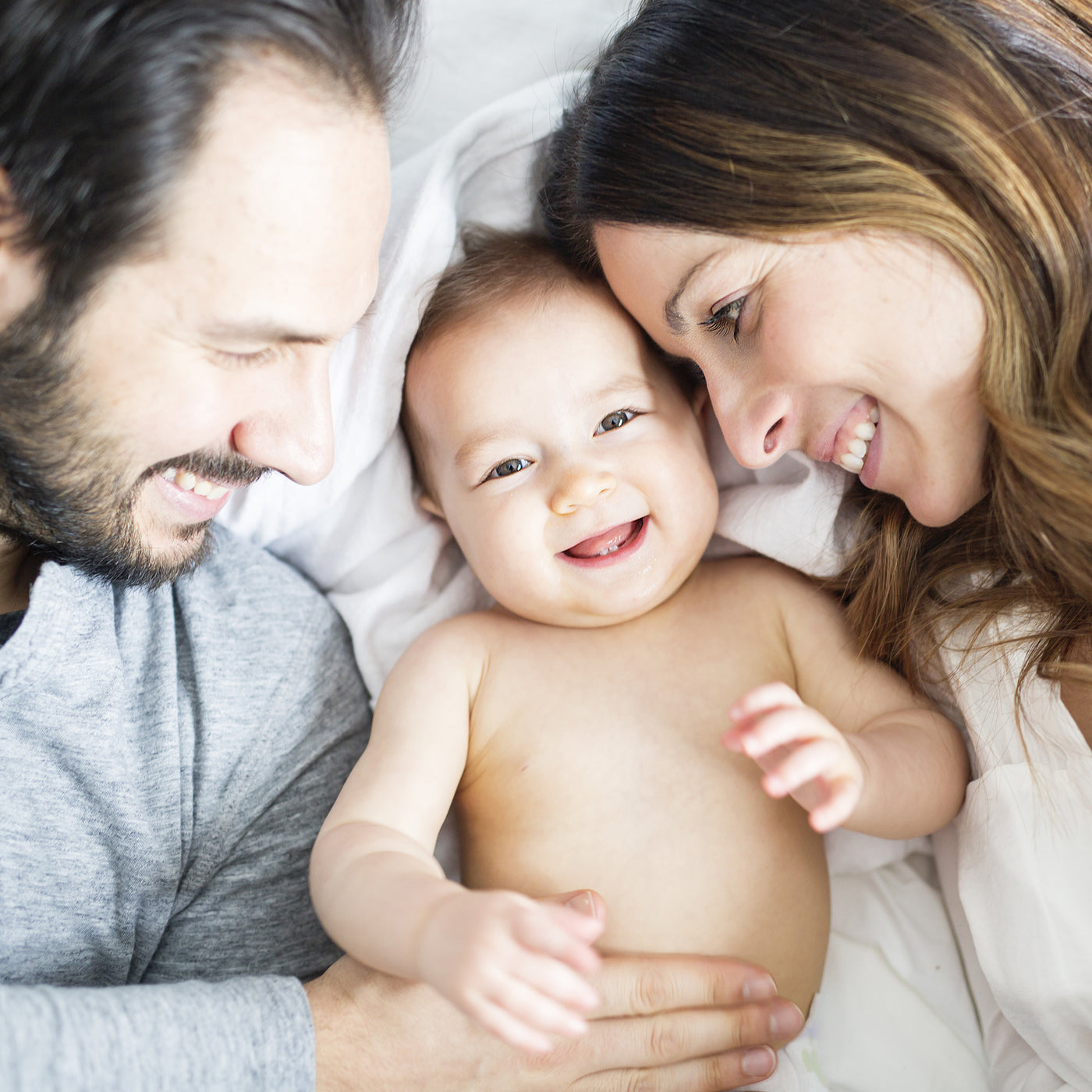 couples on bed with baby and smiling in close shot